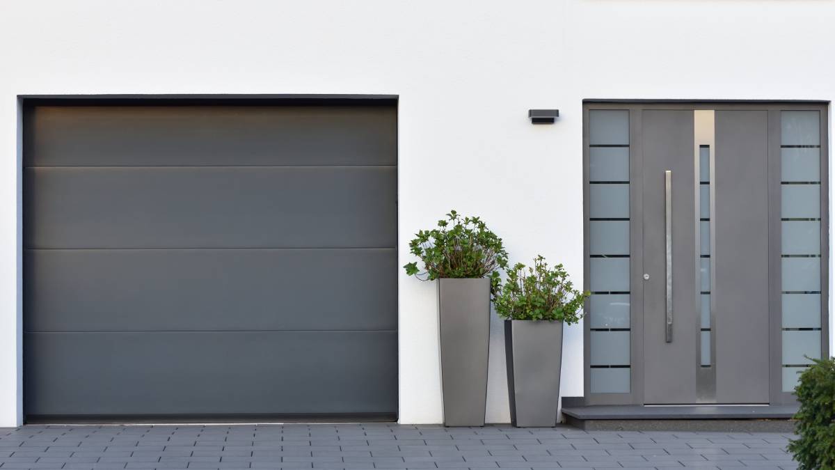 Een donkergrijze garagepoort aan huis.