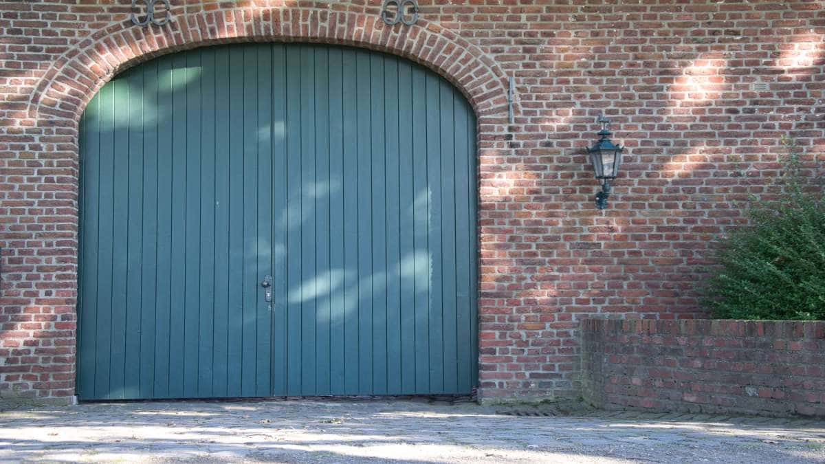 Donkergroene openslaande garagepoort.
