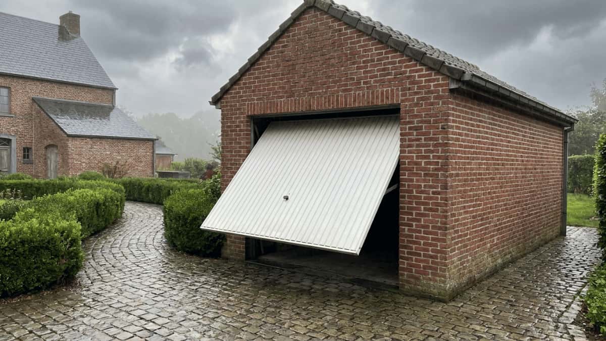 Witte kantelpoort in bakstenen garage.