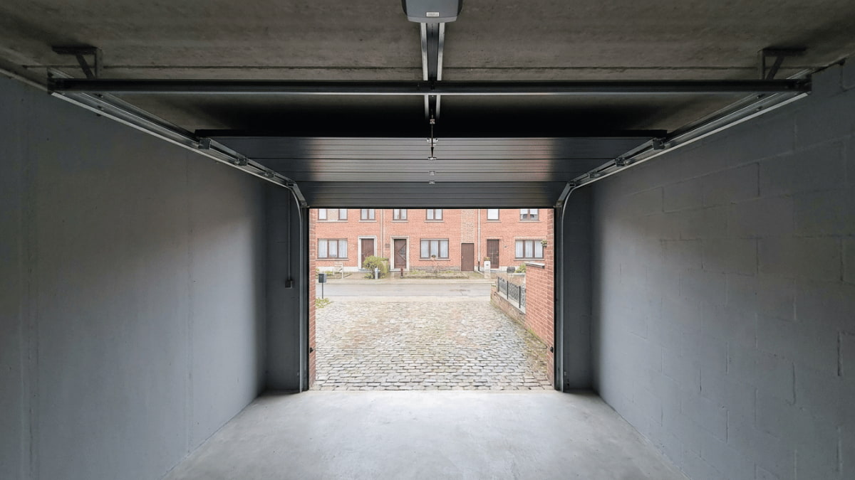 Sectionale garagepoort die open staat met zicht op straat.